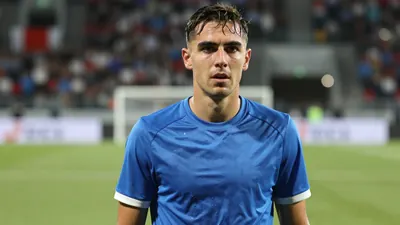 Mid-30s Sandefjord defender, lean build, intense gaze, waist-up, drenched in post-match sweat, wearing a plain blue shirt...